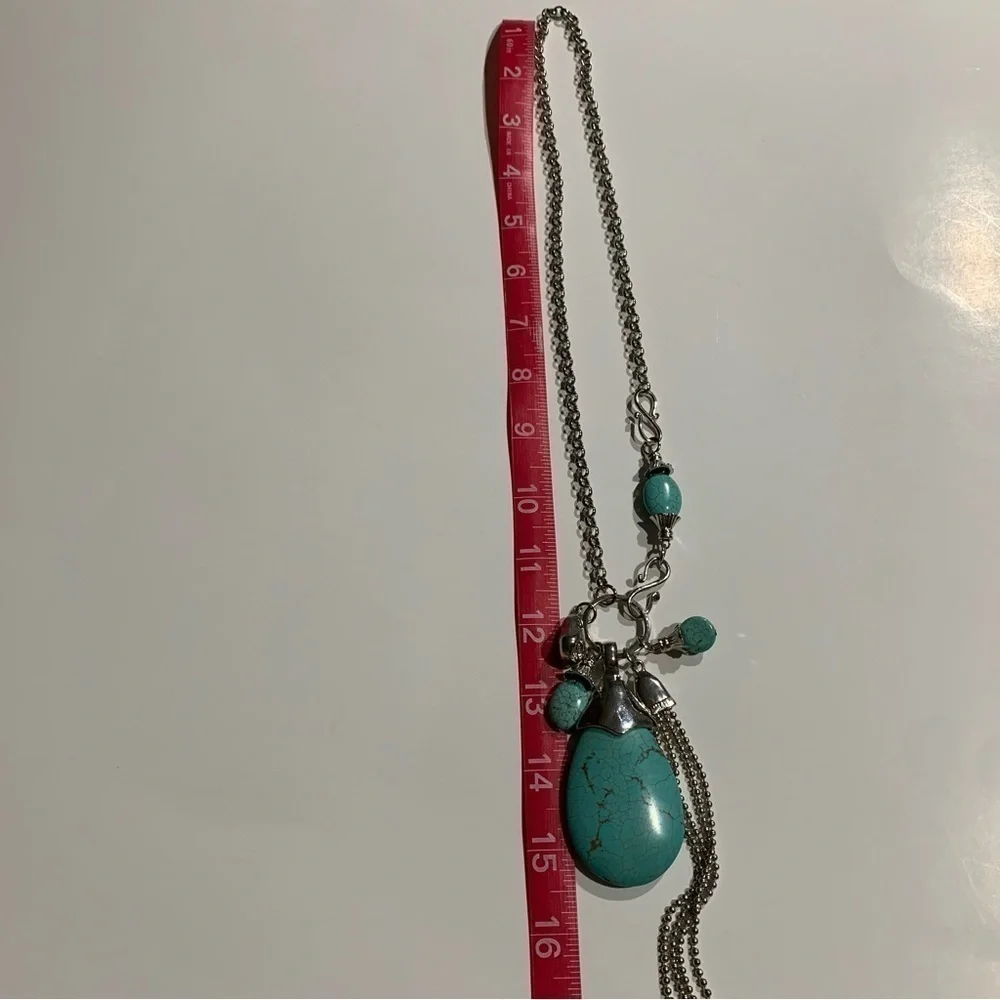 Silver tone and turquoise necklace with oversized pendant and charms.